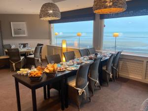 a dining room table with chairs and plates of food at Hotel De La Plage in Quiberville