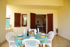 un tavolo con sedie bianche e una tovaglia blu di Villetta Turagri 22 a soli 300 m dalla spiaggia 10 posti letto a Costa Rei