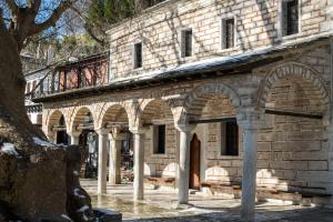 un antiguo edificio de piedra con arcos en un patio en Philos Guesthouse, en Makrinitsa