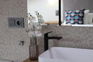 a vase with flowers in it next to a sink at La Panadería in El Rompido