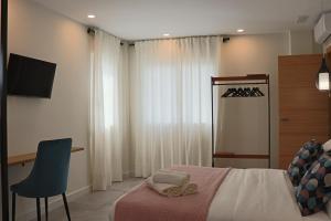 a bedroom with a bed and a chair and a television at La Panadería in El Rompido