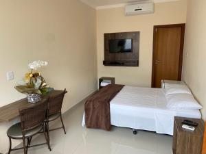 a bedroom with a bed and a table and a tv at Pousada Encantos de Capitolio in Capitólio