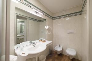 a bathroom with a sink and a toilet and a mirror at Grand Hotel Liberty in Riva del Garda