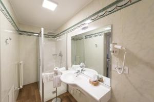 a white bathroom with a sink and a shower at Grand Hotel Liberty in Riva del Garda