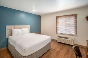 een slaapkamer met een wit bed en een raam bij WoodSpring Suites Corpus Christi in Corpus Christi