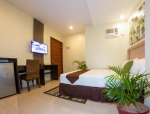 a bedroom with a bed and a desk and a tv at Verovino Suites in Cebu City