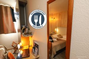 a hotel room with a bed and a sign on a mirror at Hotel Restaurant Kyriad Brive Centre in Brive-la-Gaillarde