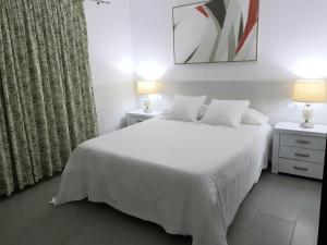 TuinejeにあるTarajalejo Eco Ocean Aのベッドルーム1室(白いベッド1台、ナイトスタンド2つ、ランプ2つ付)