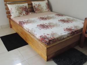 a bed with a wooden frame with flowers on it at HAPPY WELCOME Biétry 3 - MARCORY ZONE 4 in Abidjan
