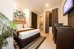 a bedroom with a bed and a flat screen tv at Verovino Suites in Mandaue City