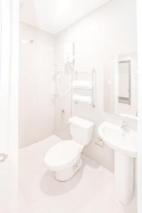 La salle de bains blanche est pourvue de toilettes et d'un lavabo. dans l'établissement Verovino Suites, à Cebu