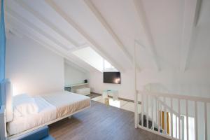 a white bedroom with a bed and a staircase at Grand Hotel Liberty in Riva del Garda