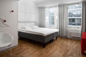a bedroom with a bed and two windows at Omena Hotel Pori in Pori