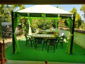 una mesa y sillas bajo un dosel verde en Prostor Guest House, en Byala