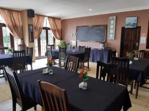 una sala de conferencias con mesas, sillas y una pantalla en The Guest House Standerton en Standerton