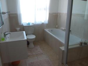 a bathroom with a toilet and a tub and a sink at Trev's Place in St Francis Bay