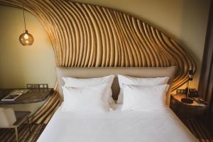 a bed with a wooden headboard and white pillows at Vila Foz Hotel & SPA - member of Design Hotels in Porto