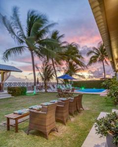 una fila de sillas de mimbre con palmeras y una piscina en Ipioca Beach Village, en Maceió
