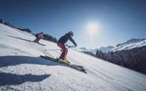 ダボスにあるDavoser Hüsli by Mountain Hotelsの雪に覆われた坂道を2人がスキーで下りている
