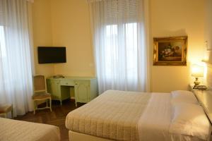 a bedroom with two beds and a desk and a television at Grand Hotel Liberty in Riva del Garda