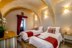 a bedroom with two beds with red and white sheets at Viewpoint Boutique Living in Xlendi