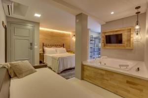 a bedroom with a tub and a bed and a television at Solar Beach Hotel in Florianópolis