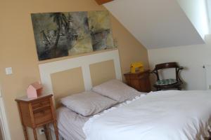 アミアンにあるLe Kiosque Amiens chambres d'hôtesのベッドルーム1室(ベッド1台付)が備わります。壁には絵画が飾られています。