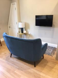 a blue couch in a living room with a tv at Beautiful Bath Apartment in iconic Milsom Street Location in Bath