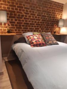 a bed with two pillows and a brick wall at DOUX COCON DE 50 m2 PARIS-LE RAINCY in Le Raincy