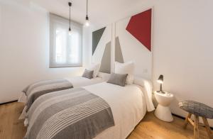 two beds in a white room with two lamps at Apartamento Tirso en Madrid in Madrid