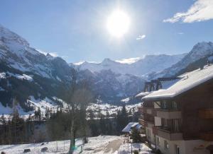 vistas a una montaña cubierta de nieve y a un edificio en Ferienwohnung Studio Selvea, en Adelboden