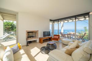 una sala de estar con muebles blancos y ventanas grandes. en Villa Illa, en L'Escala
