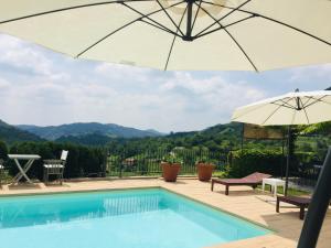a pool with an umbrella and a table and chairs at Ca' Piadera Wine Relais in Tarzo