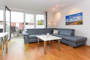 a living room with a blue couch and a table at Ferienwohnungen MARENOR in Bensersiel