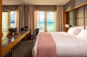 a hotel room with a bed and a desk and windows at Mount Athos Resort in Ierissos