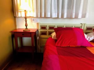um quarto com uma cama vermelha e uma mesa com um candeeiro em CASA DRUNA LEE ; CASA EN EL CAMPO em Santa Gadea