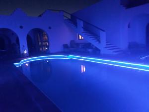 a swimming pool with blue lights in a dark room at Dar Chick Yahia Ile De Djerba in Mezrane