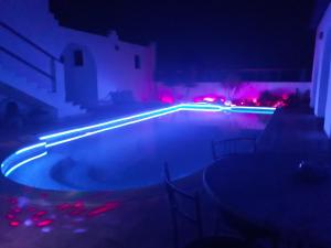a swimming pool at night with red and blue lights at Dar Chick Yahia Ile De Djerba in Mezrane