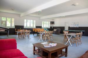 sala de estar con mesas, sillas y mesa de billar en Camping de l'île, en Bannay