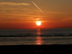a sunset on the beach with a plane in the sky at Pension Schier in Zandvoort