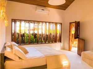 ein Schlafzimmer mit einem Bett und einem großen Fenster in der Unterkunft Casa do PESCADOR Atins - c/ todo conforto e super localização in Atins