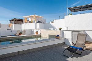 a chair sitting on a patio next to a swimming pool at Apartamentos Wamba in Conil de la Frontera