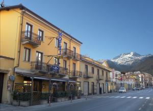eine Reihe von Gebäuden auf einer Straße mit einem Berg in der Unterkunft Hotel Susa & Stazione in Susa