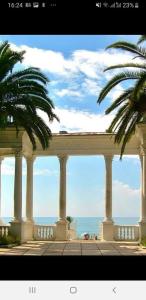 a building with columns and palm trees in front of the ocean at Гостевой дом Анастасия in Sukhum