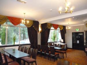 comedor con mesa, sillas y ventanas en West Park Hotel, en Clydebank