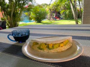 un panino su un piatto su un tavolo con una tazza di caffè di Bada Hostel & Kite School a Cumbuco