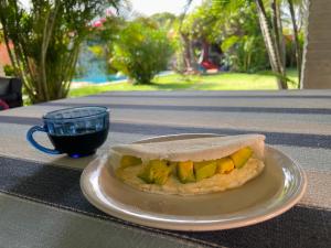 a sandwich on a plate on a table with a cup of coffee at Bada Hostel & Kite School in Cumbuco