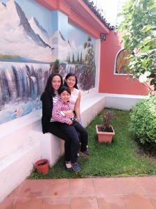 Dos mujeres y un niño sentados junto a una pared. en Hotel Andino, en Quito