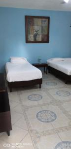a room with two beds and a blue wall at La Casa del Turix in Mérida