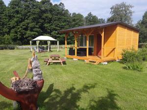 a small cabin in a field with a statue in the grass at Kempings Jūrmalnieki in Mazirbe